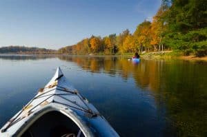 Kayaking in calm waters with fall leaves on the trees